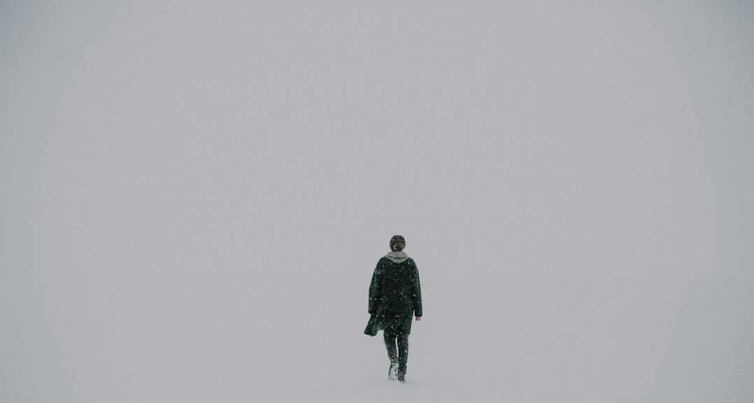 Anonymous silhouette of a person walking alone through fog