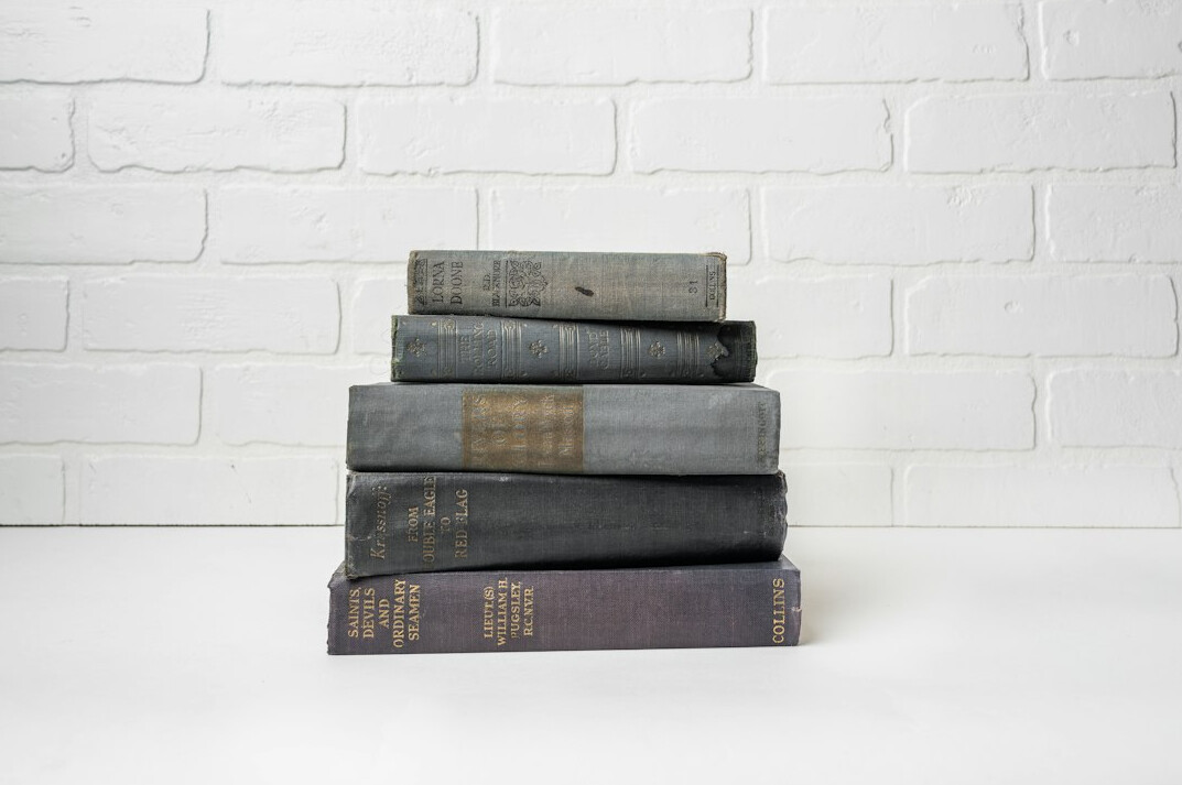Stack of old hardcover books with worn spines